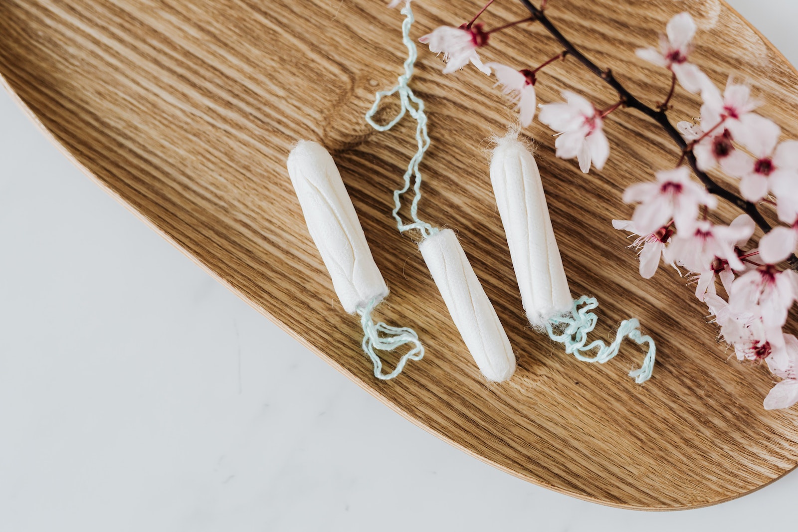 From above of hygienic cotton tampons placed on bamboo board with small pink flowers