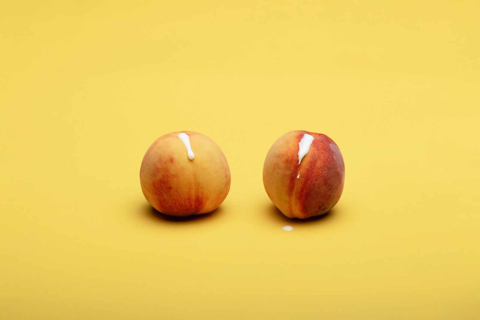 2 red apples on yellow surface